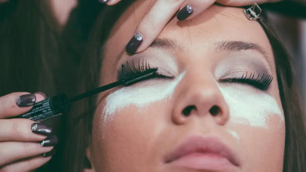 A woman is getting her eyelashes done by a makeup artist.