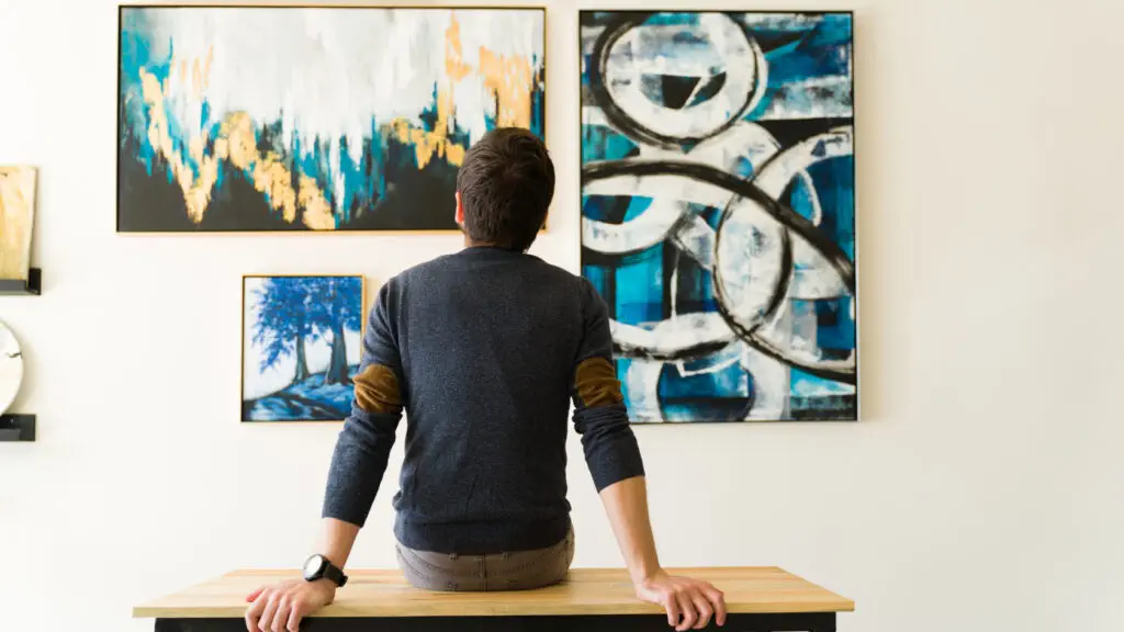 A man sitting at a table looking at art on the wall.