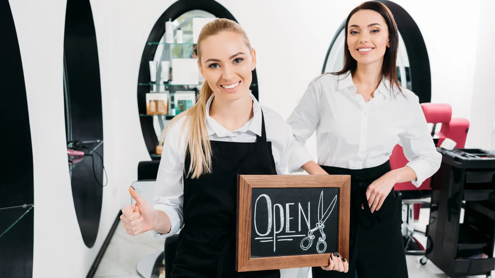 Two women standing next to a sign in a salon.