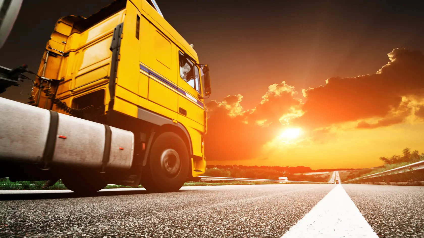 A yellow truck is driving down the road.